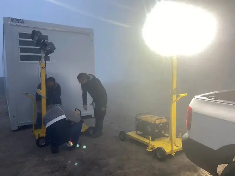 Equipe da Revlo ajustando duas torres de iluminação acesas na neblina